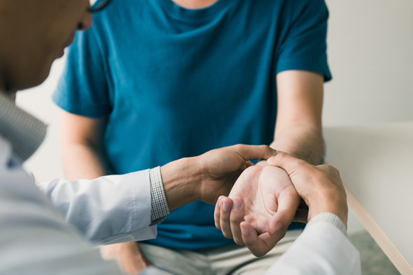 Physical Therapist Checks The Patient Wrist By Pressing The Wris